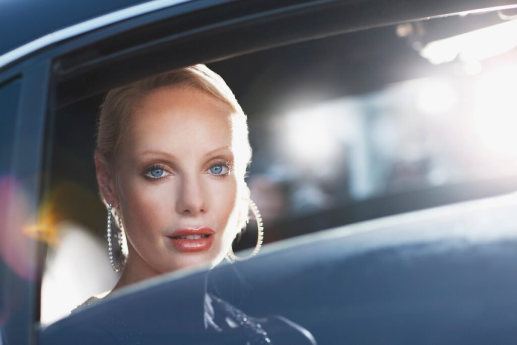 Blonde haired blue eyed glamorous woman in the back of a limo arriving at celebrity event